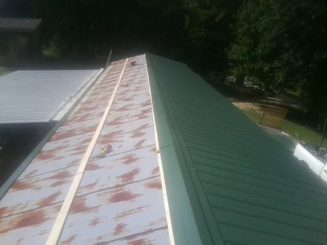 Old rusted panels beside newly installed green metal roofing — Wind Damage Roof Repair by Roofing Brothers in Ponte Vedra Beach