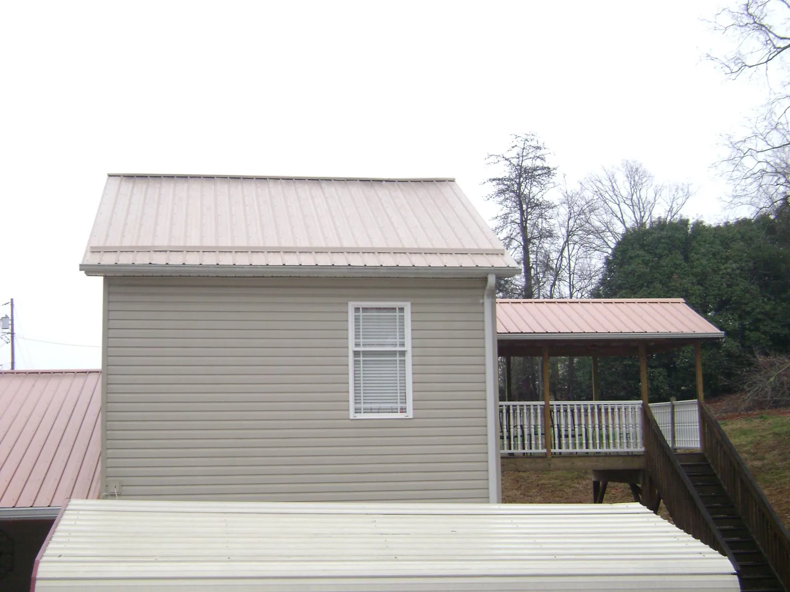 Tan metal roofs on a two story addition and attached porch, from a Roof Replacement job in Ponte Vedra Beach