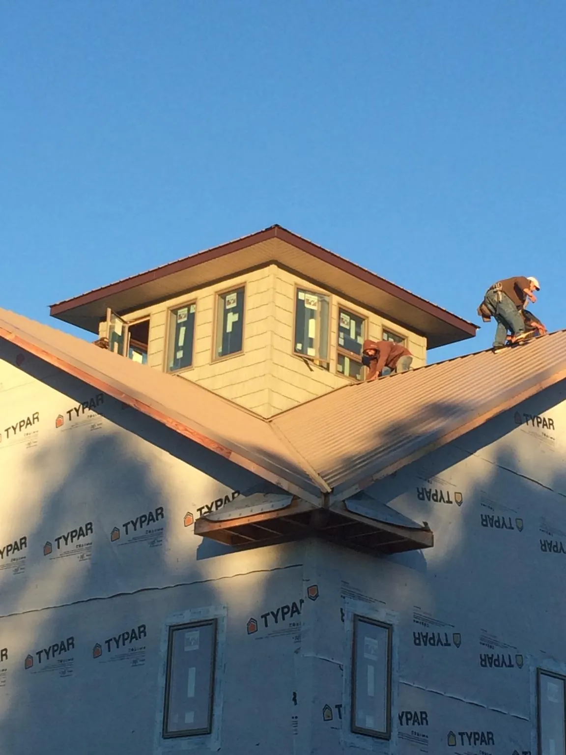 Roofers working around a rooftop cupola on a new metal roof at sunset — Roof Waterproofing in Ponte Vedra Beach by Roofing Brothers